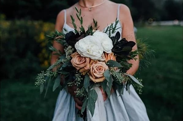 Bride holding a bouquet of white and peach flowers.