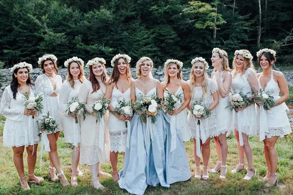 Group of women in white dresses and flower crowns outdoors.