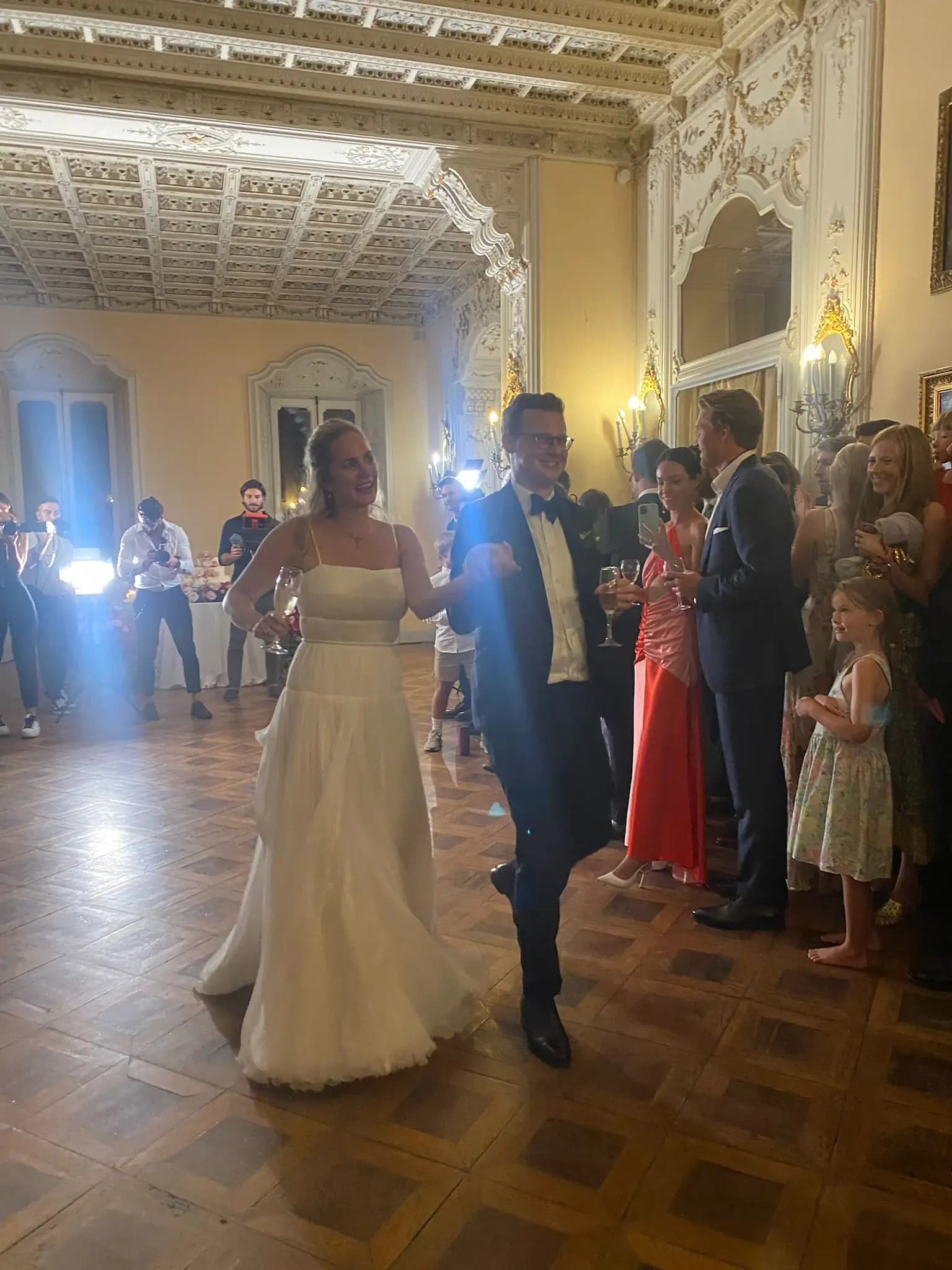 Bride and groom dancing with guests at a reception.