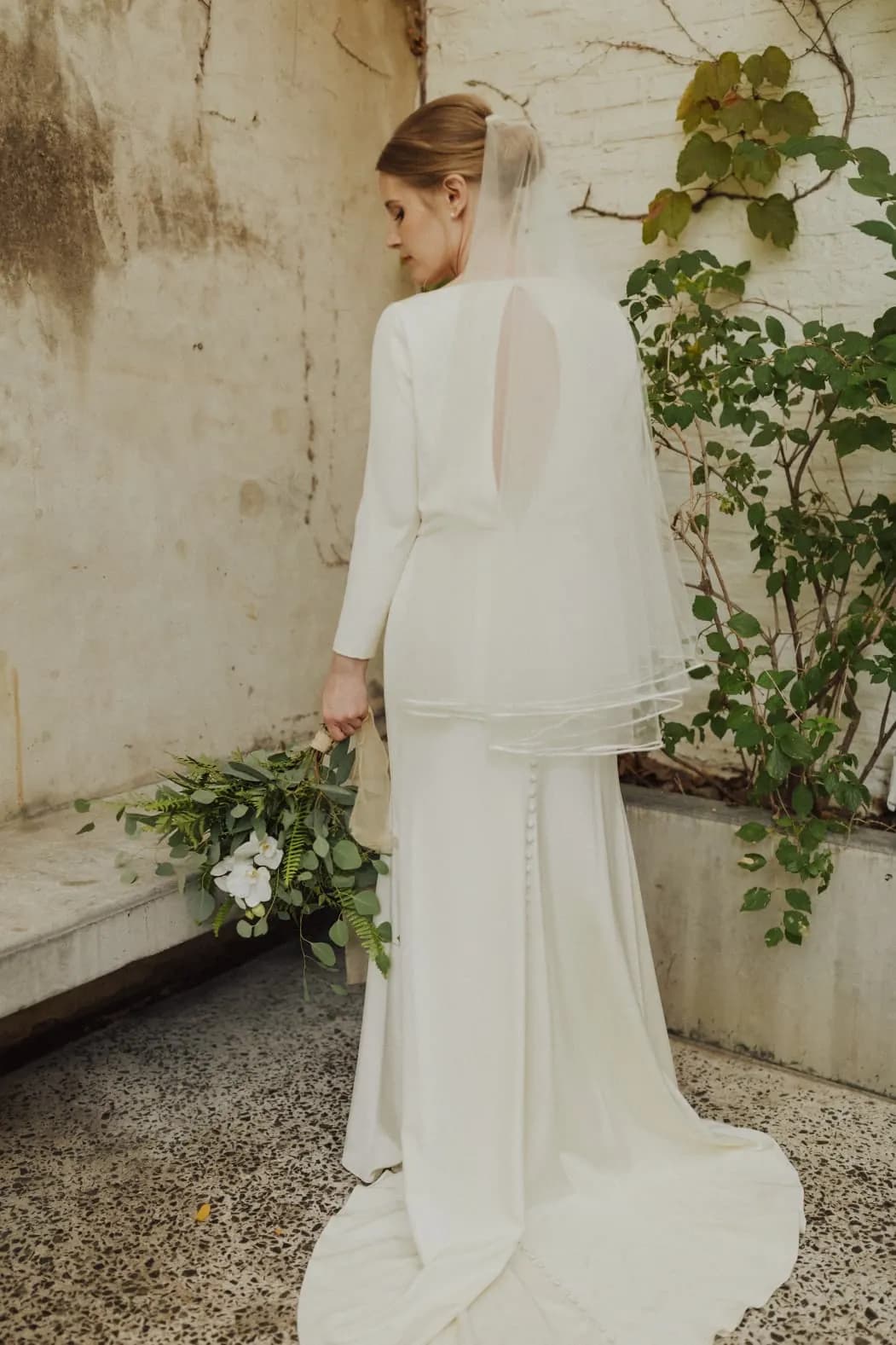 Bride viewed from behind in a gown and veil.