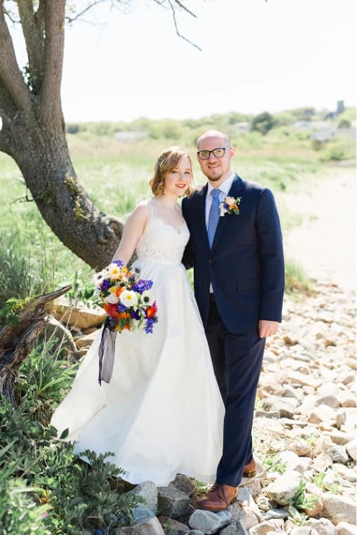 Bride and groom standing beside a tree.