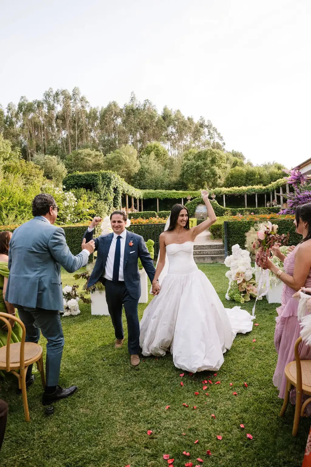 Bride and groom walking through a garden ceremony with guests.