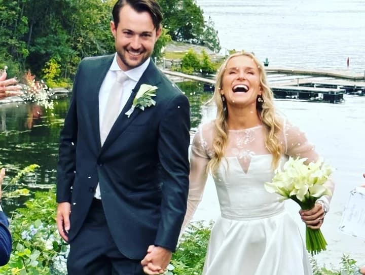 Bride and groom walking beside the water.