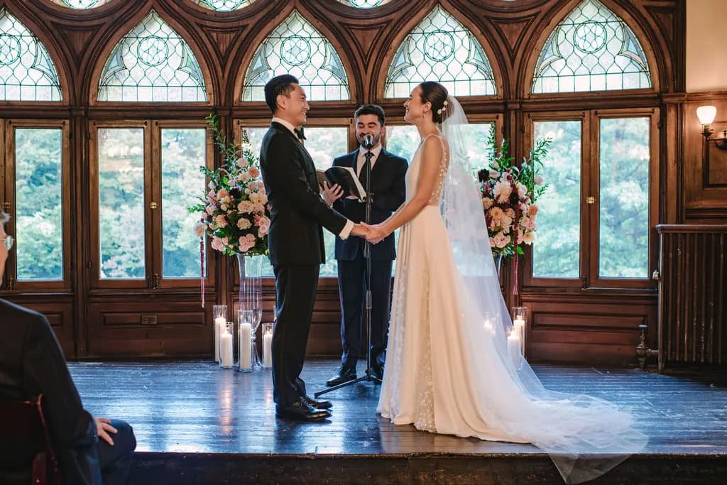 Bride and groom exchanging vows before stained-glass windows.
