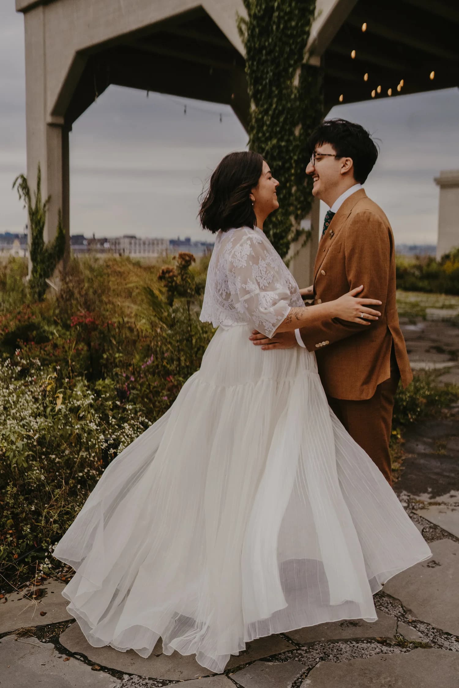 Bride and groom embracing on a terrace with the city behind them.