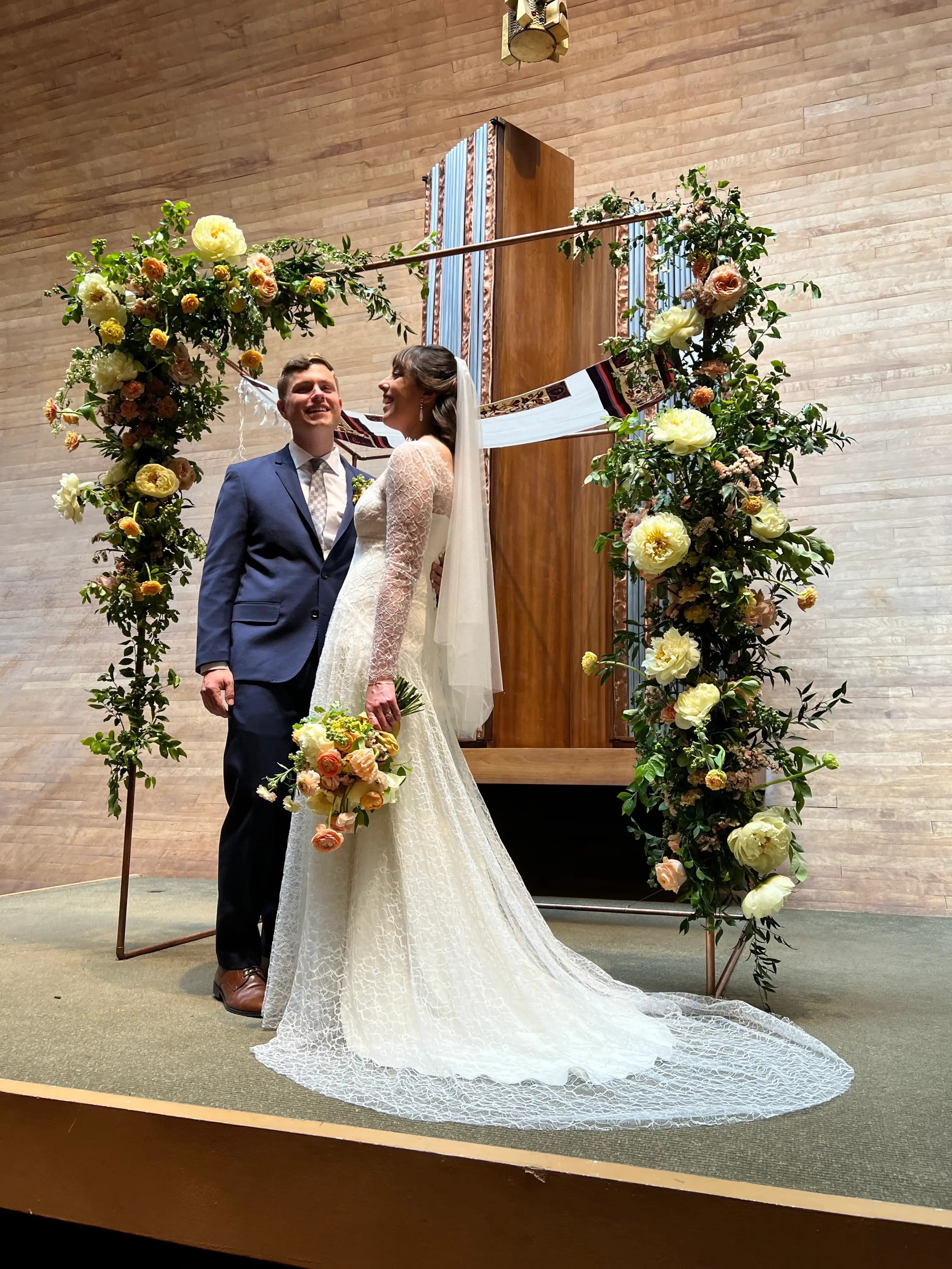 Bride and groom beneath a floral arch during their ceremony.