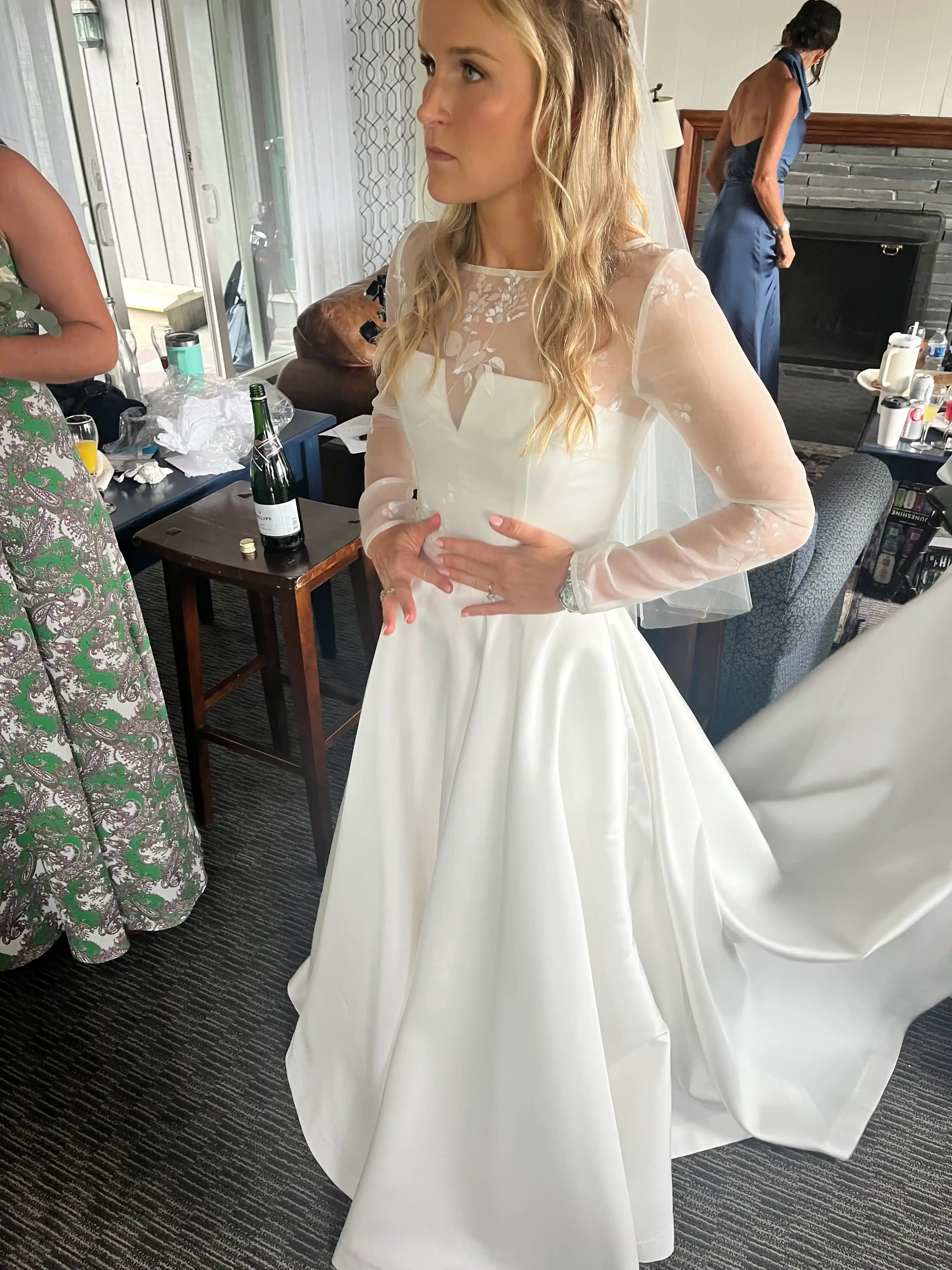 Bride adjusting her lace gown indoors before the ceremony.