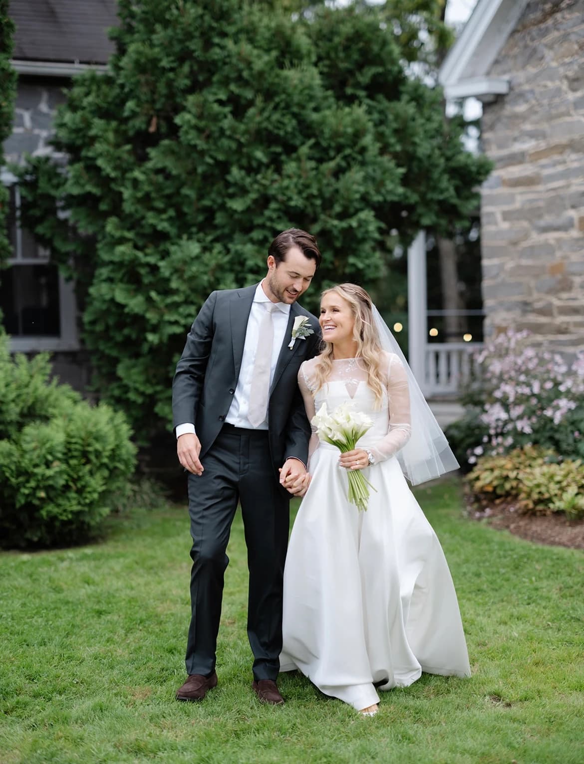 Bride and groom walking together through a garden.