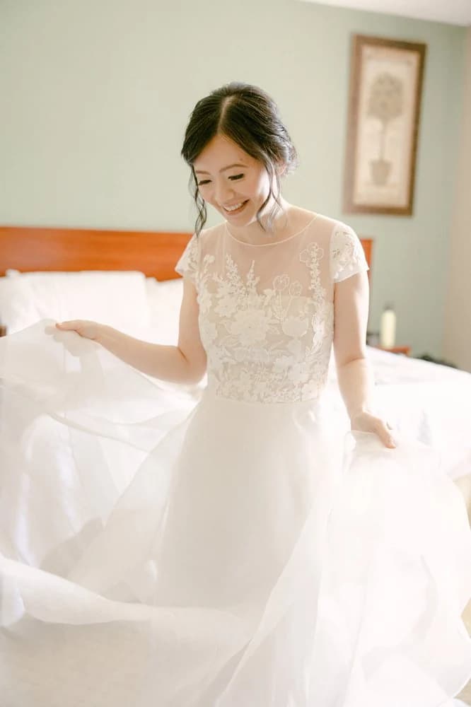 Bride lifting her skirt while standing on a bed.
