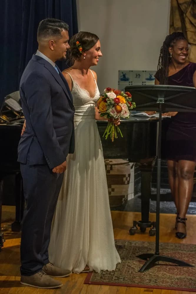 Bride and groom standing beside a musician at their ceremony.