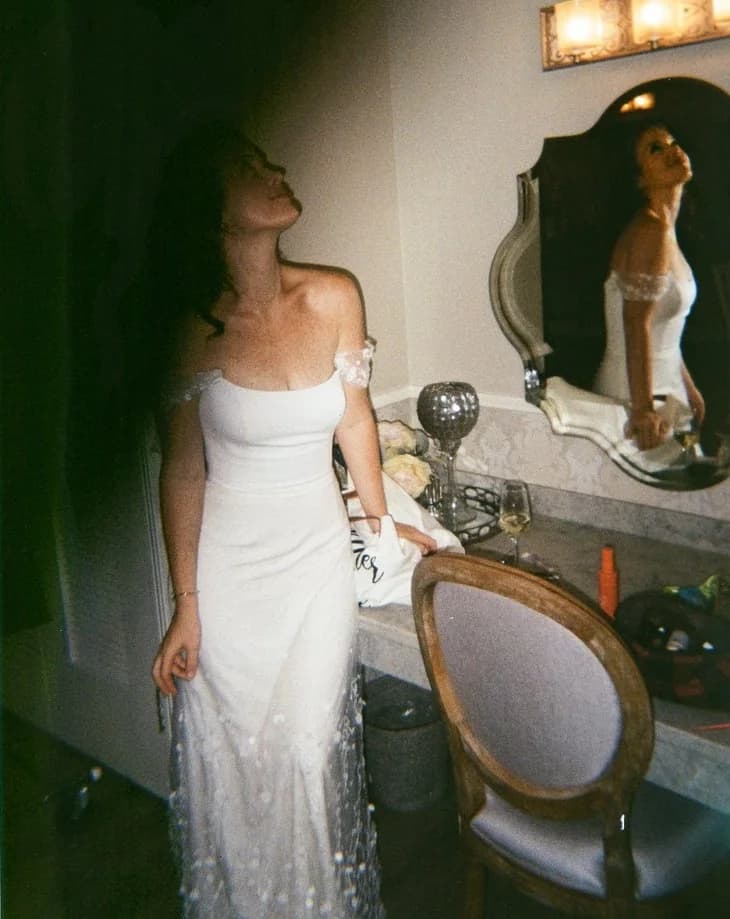 Cropped portrait of a bride beside a mirror in a softly lit room.