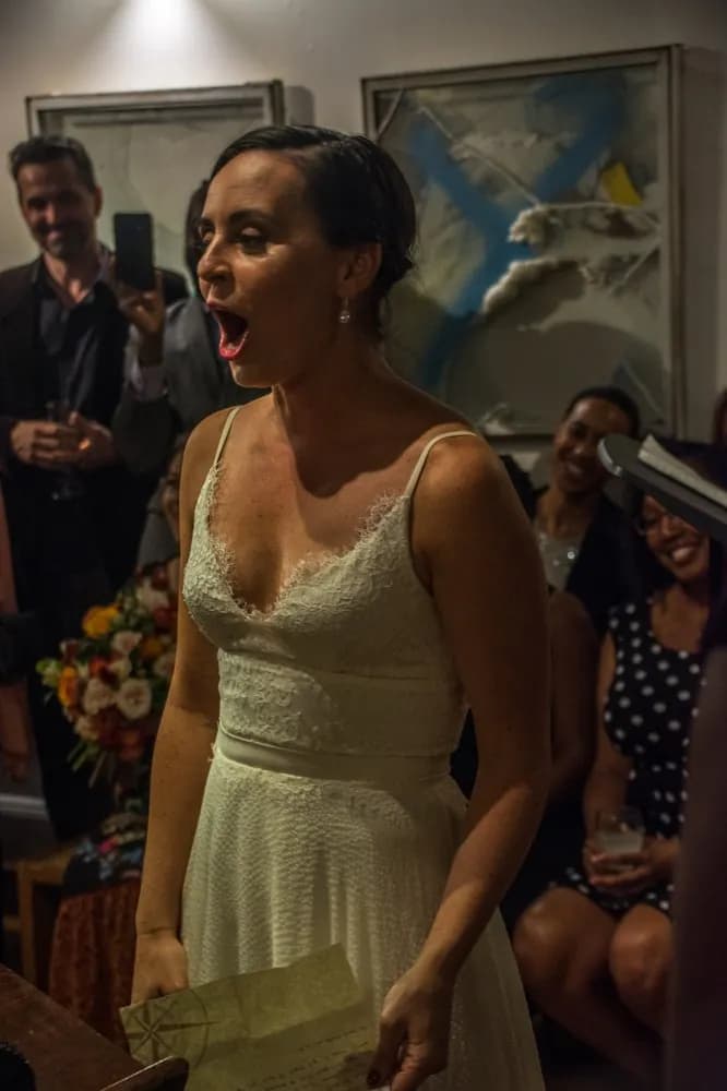 Bride speaking to guests during an indoor celebration.