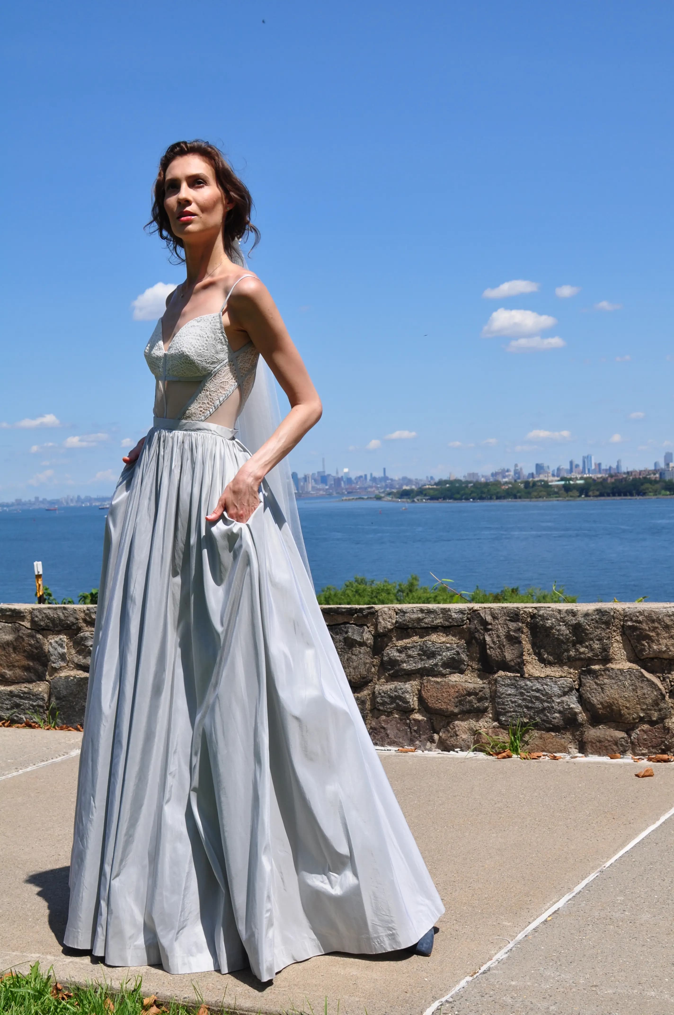 Bride in a silver gown with the city skyline behind her.