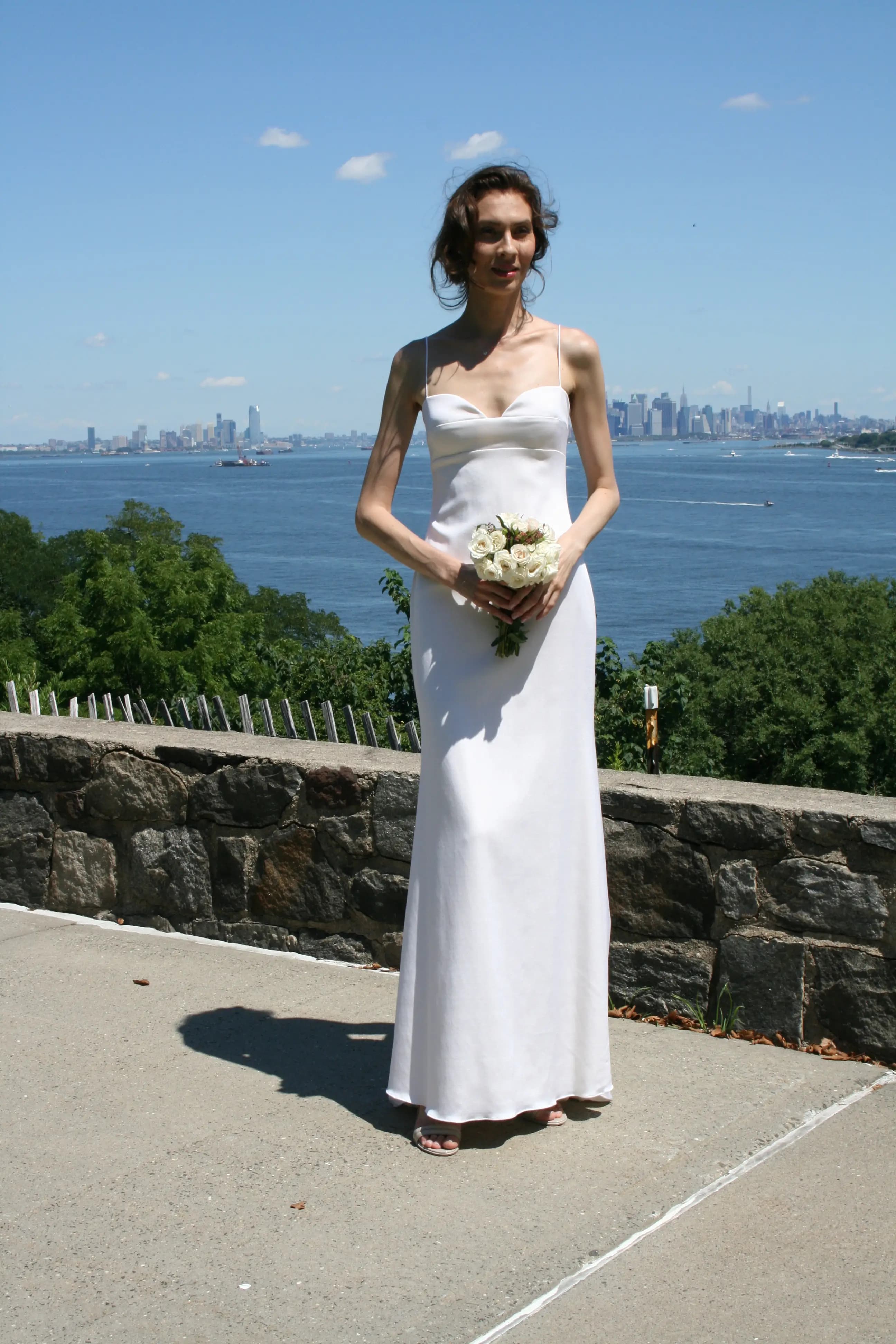 Bride holding a bouquet beside the city skyline.