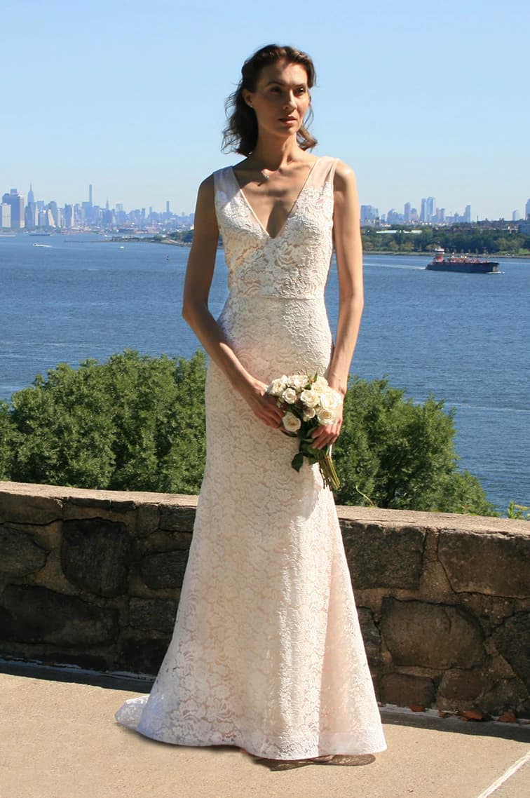 Bride holding a bouquet before a city skyline.