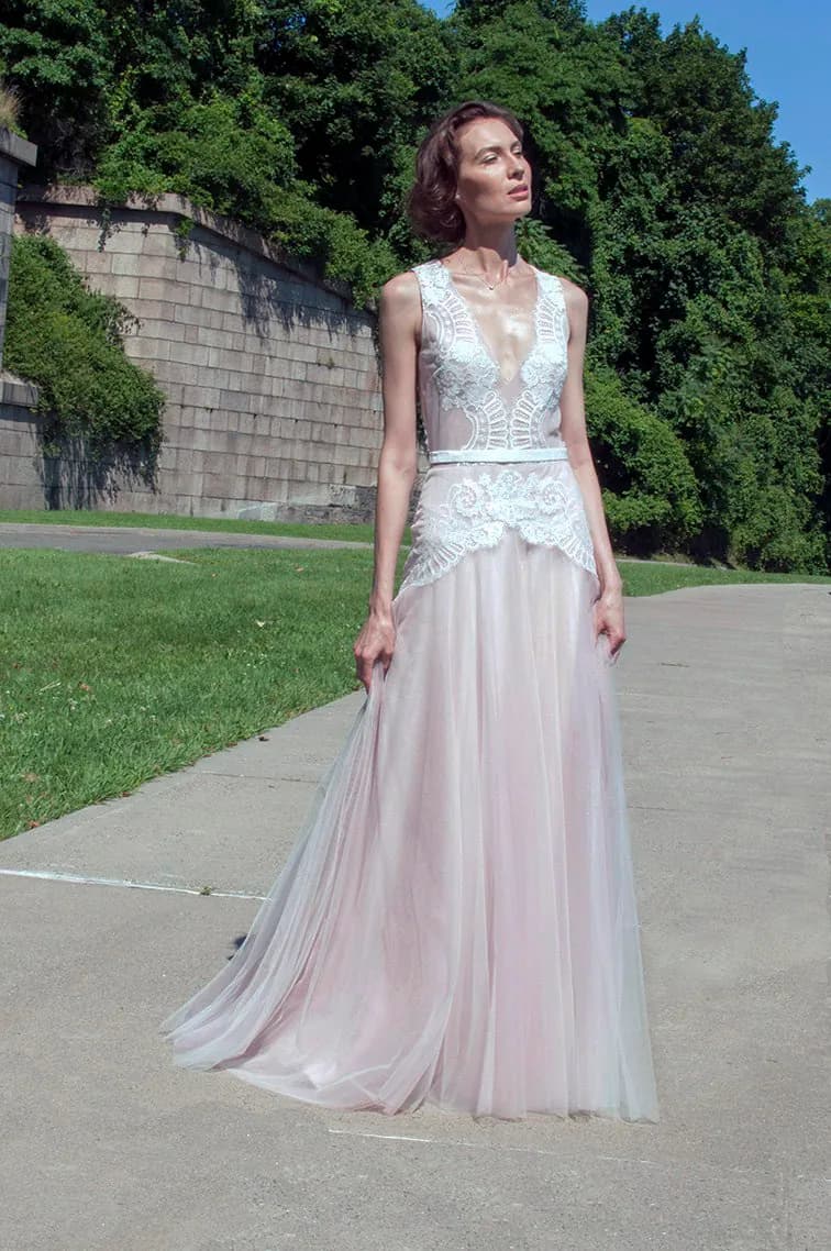 Bride in a pink lace gown on a garden path.