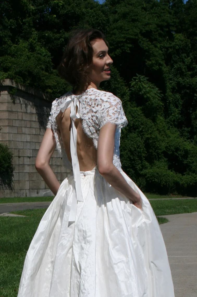 Bride showing the lace back of a gown outdoors.