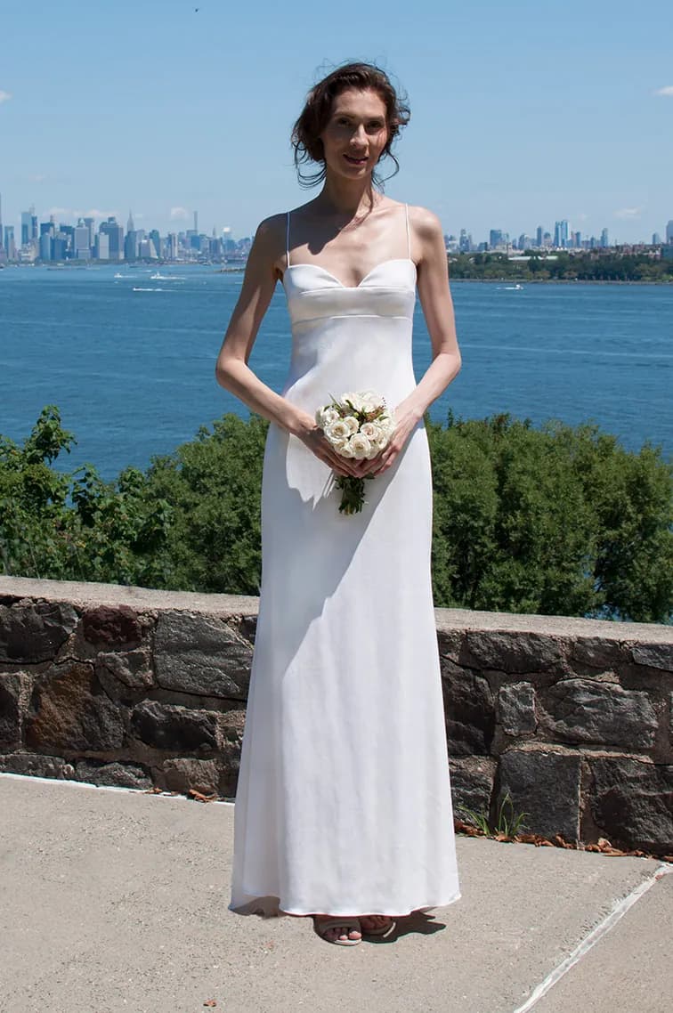 Bride holding a bouquet in front of the New York skyline.