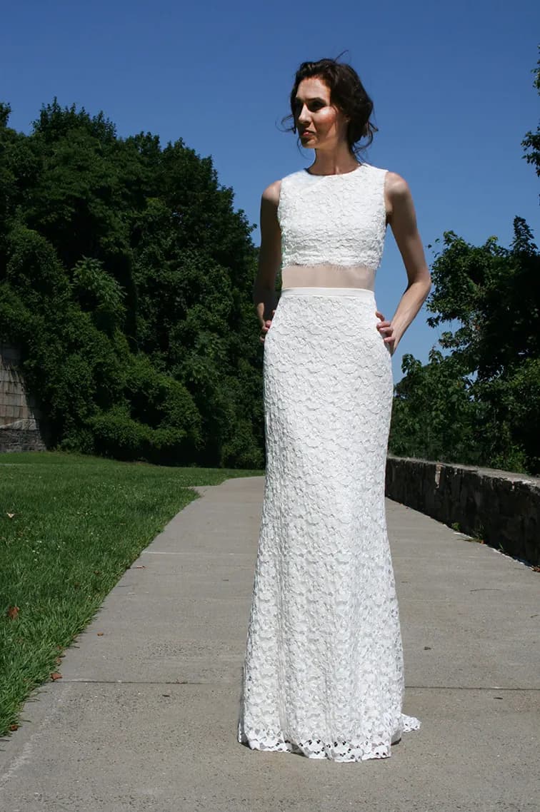 Bride in a lace two-piece gown on a garden path.
