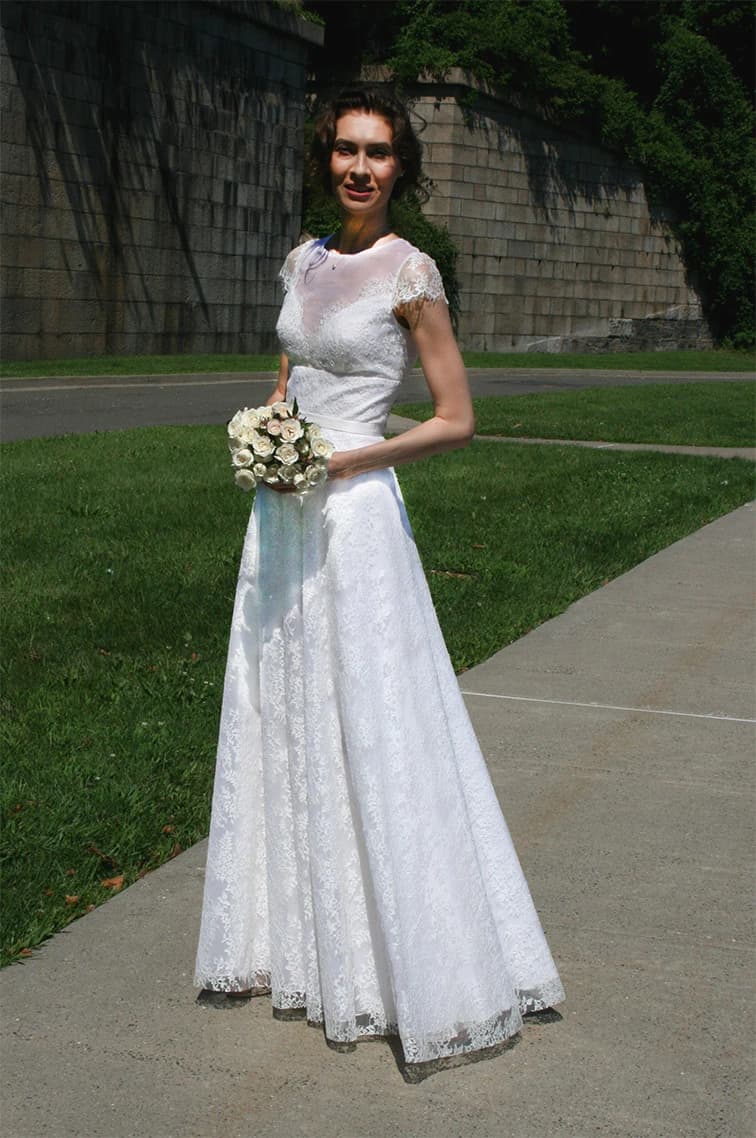 Bride holding a bouquet on a grassy path.
