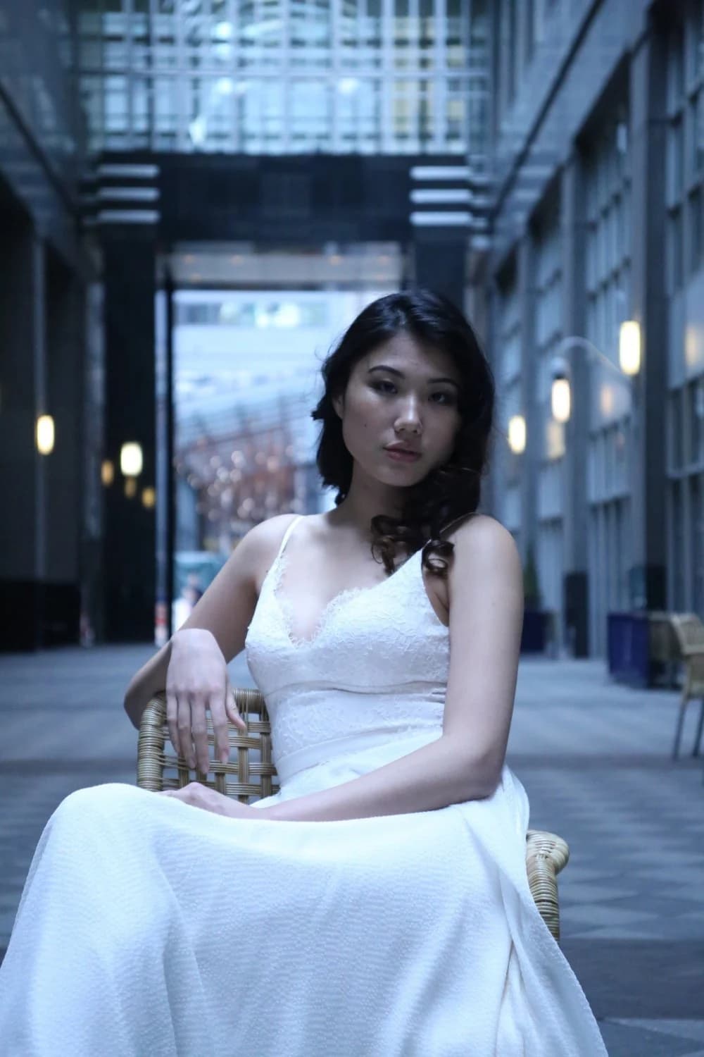 Bride seated in a white gown in a city arcade.