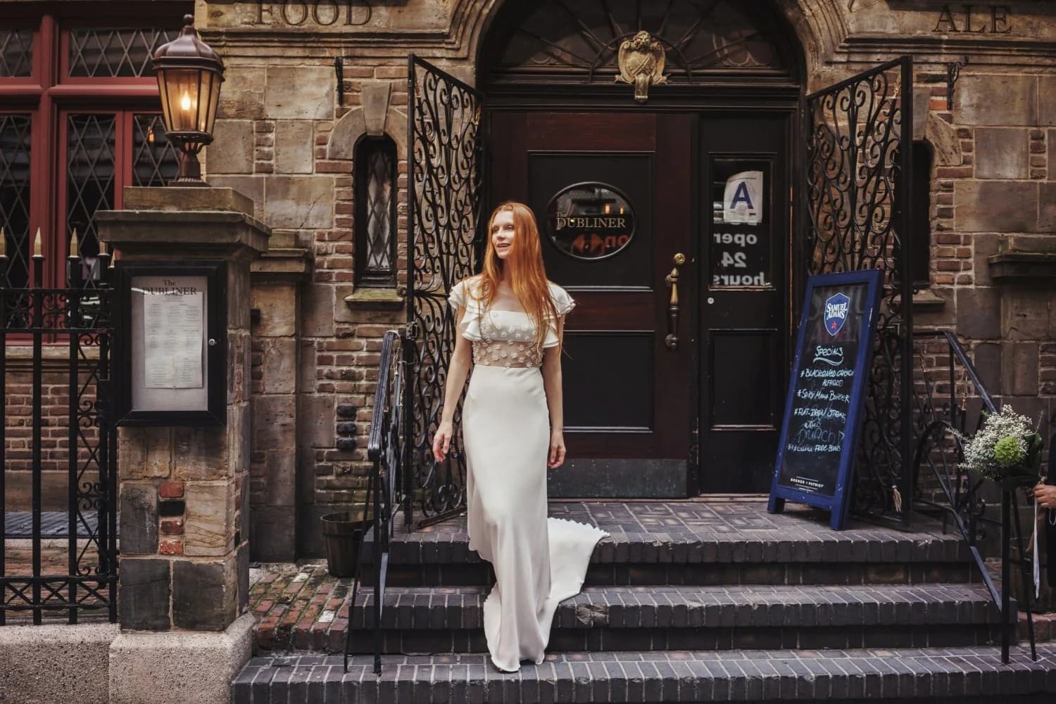 Bride standing outside a brick building in a ruffled-sleeve gown.