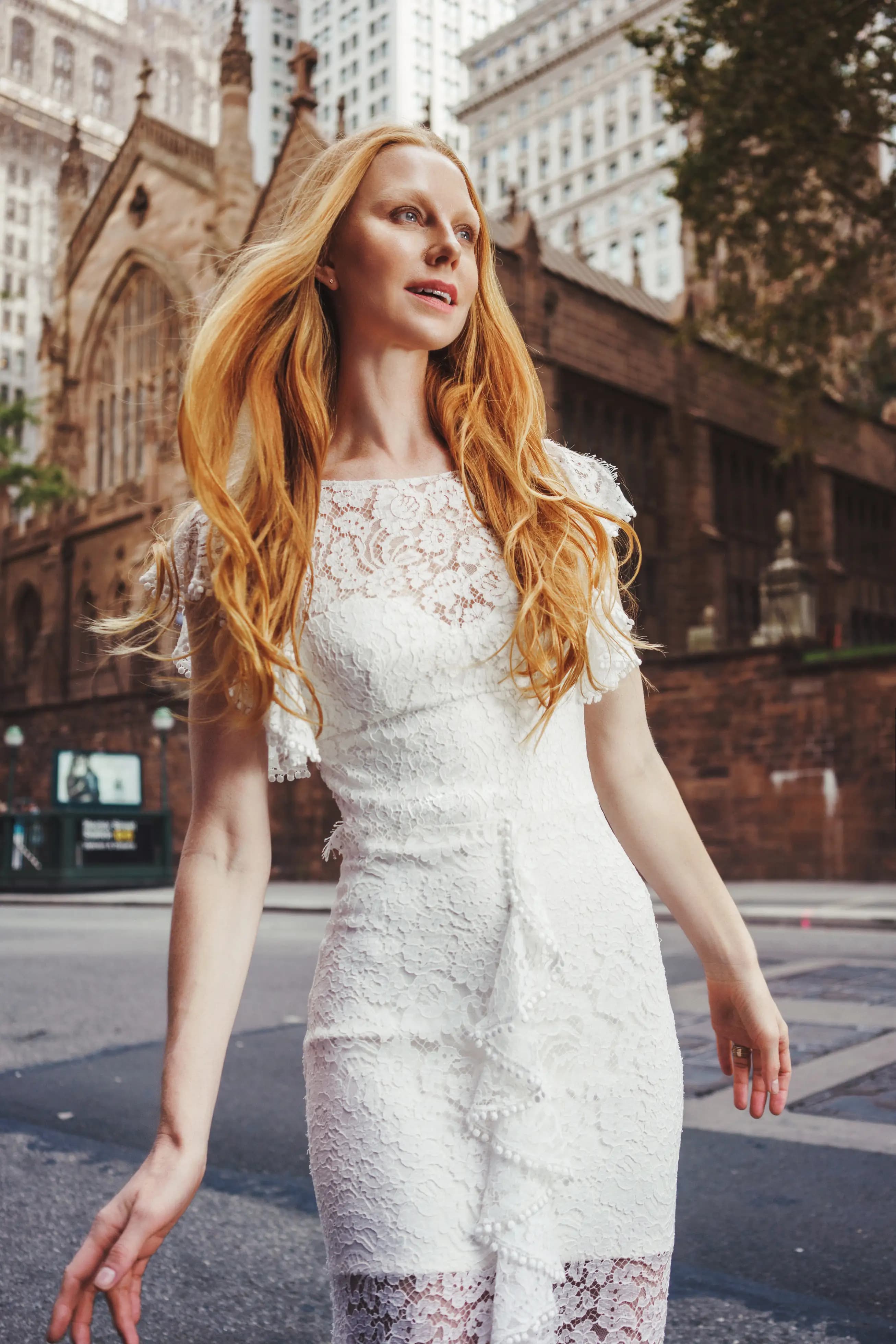 Close view of a bride in a floral lace gown near a city church.