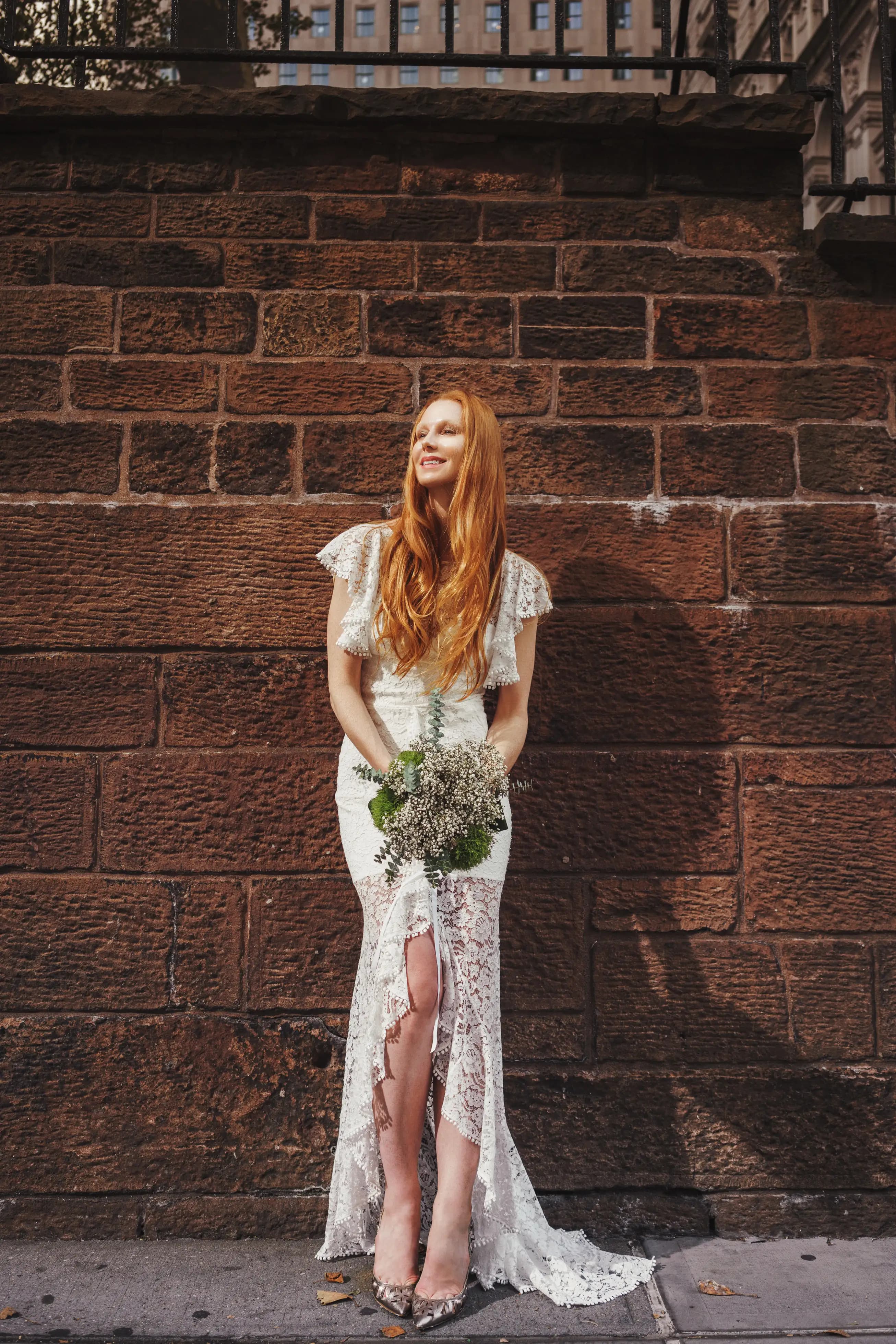 Bride holding a bouquet before a stone wall.
