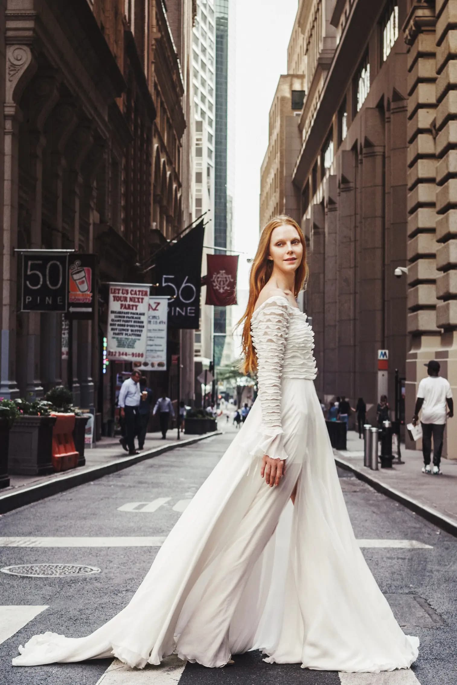 Bride in a long-sleeve gown crossing a downtown street.