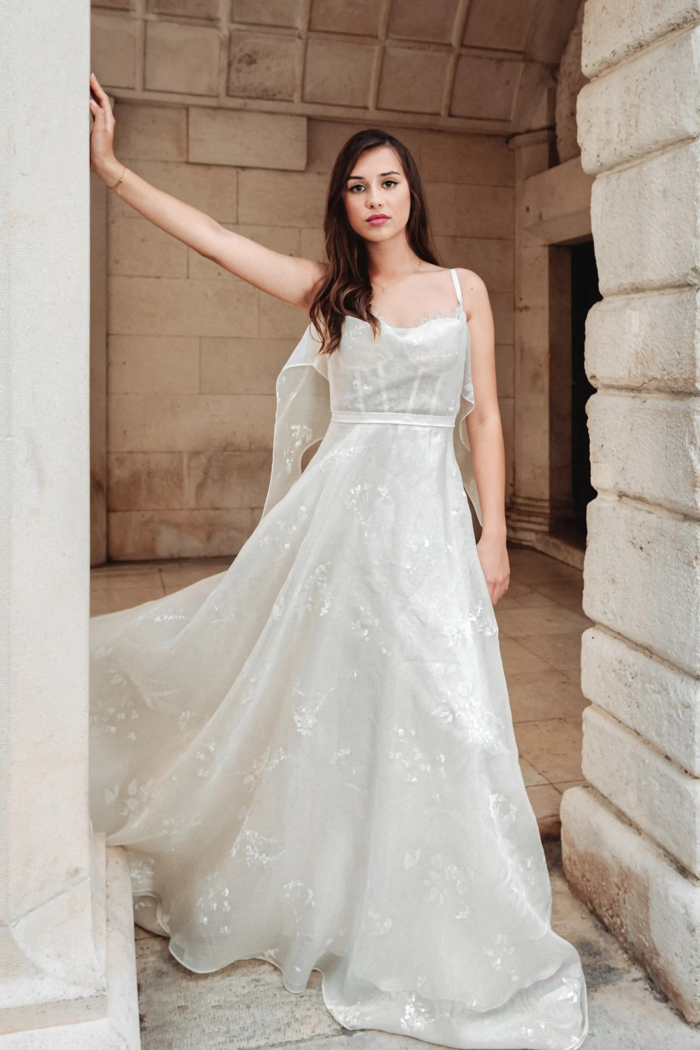 Bride in an embroidered gown among stone columns.