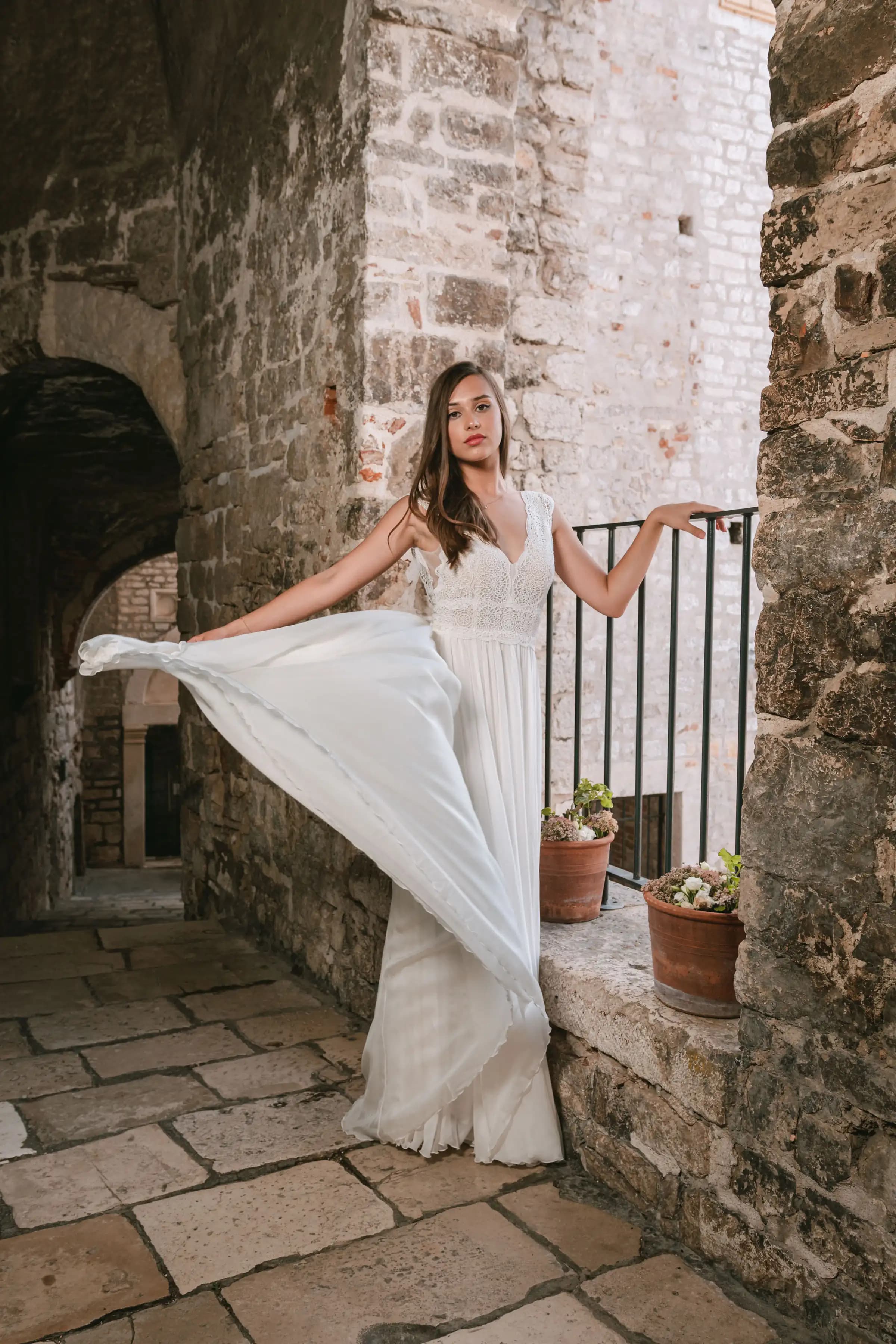 Bride lifting her skirt in a stone passageway.