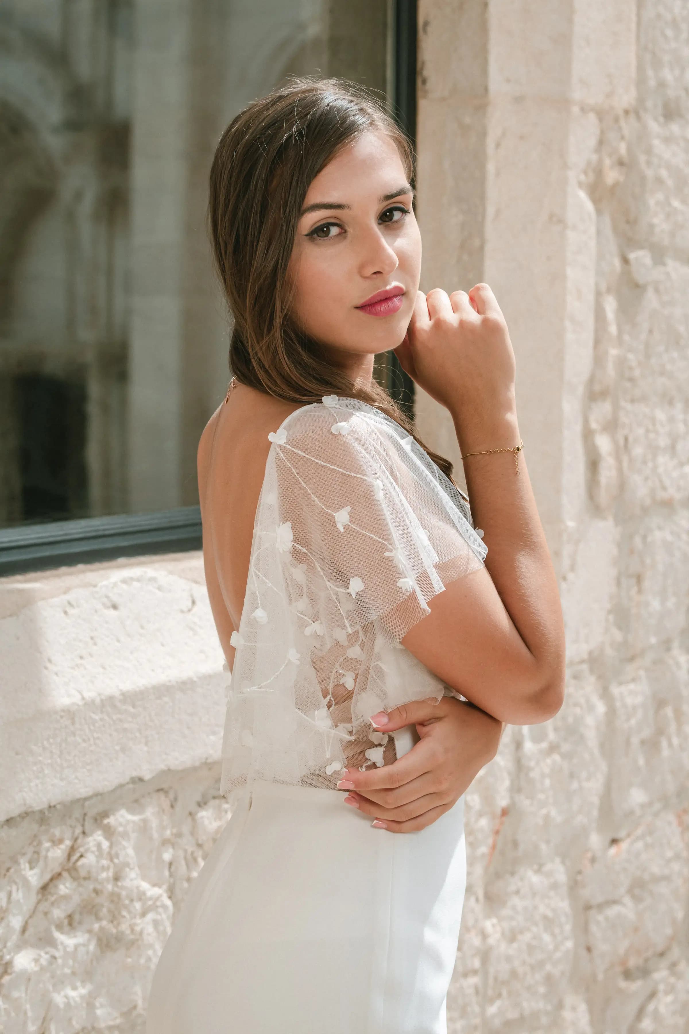 Close portrait of a bride in a sheer floral sleeve.