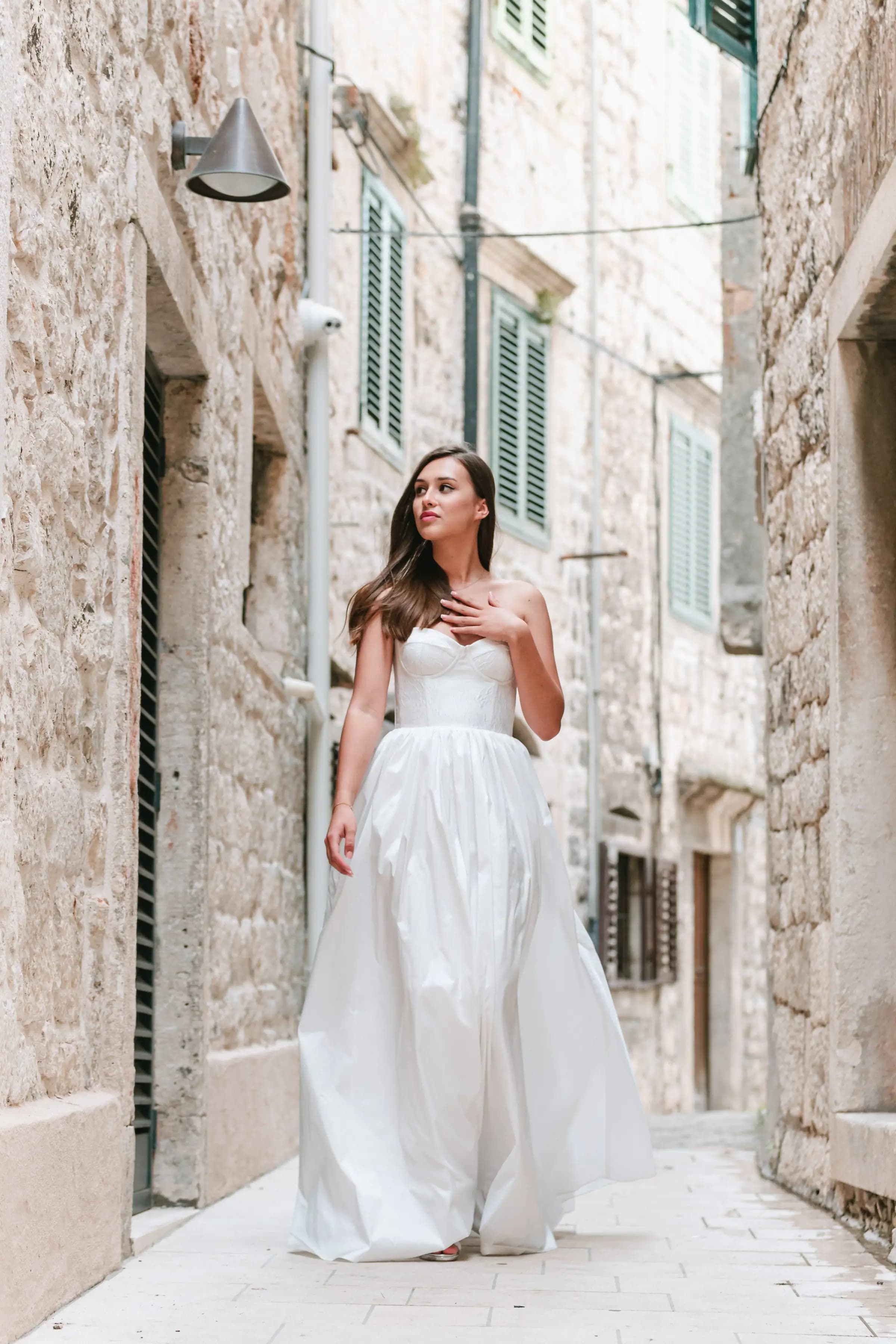 Bride in a full gown walking through a narrow stone lane.